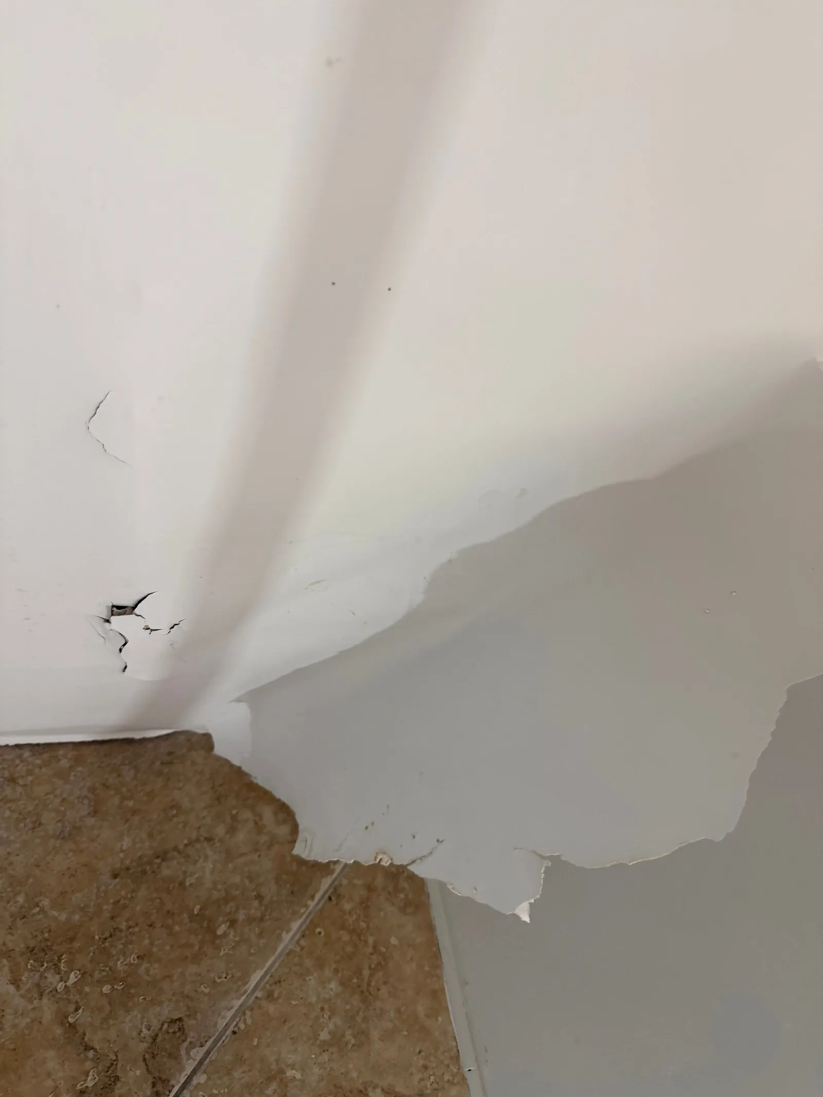 Peeling paint and damaged drywall at the base of a wall