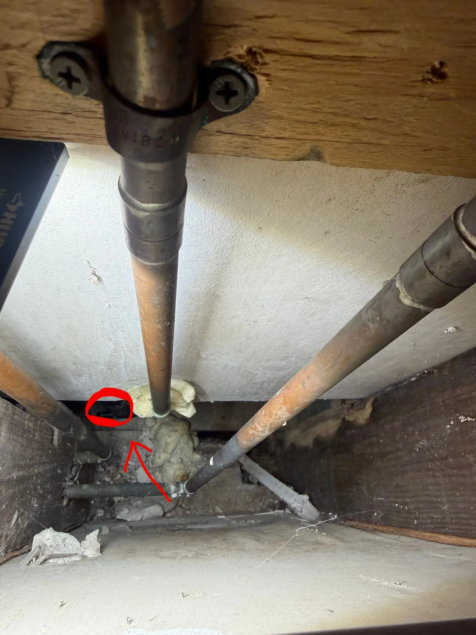Bathtub drain pipe seen through an access panel, marked in red