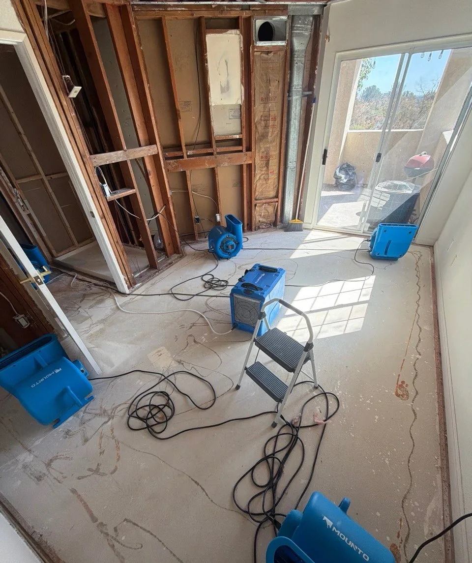 Bedroom with wet drywall removed to the framing and a dehumidifier running