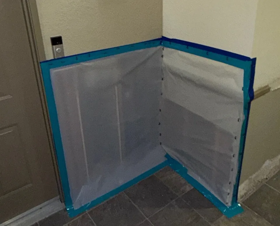 Plastic containment sealed with tape at a condo entry corner